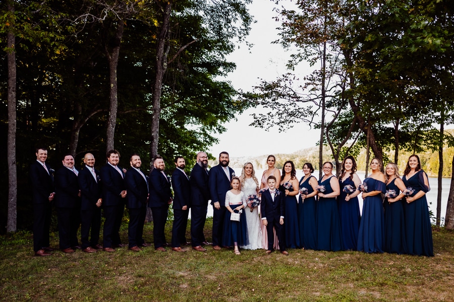 bridal party in front of river at the waters edge estate wedding venue