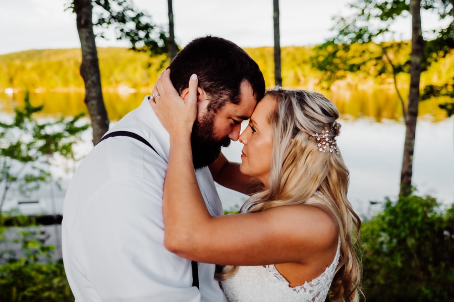 bride and groom foreheads touching in front of water