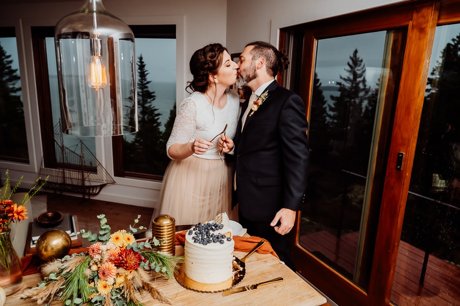 bride and groom kissing after sharing bite of wedding cake