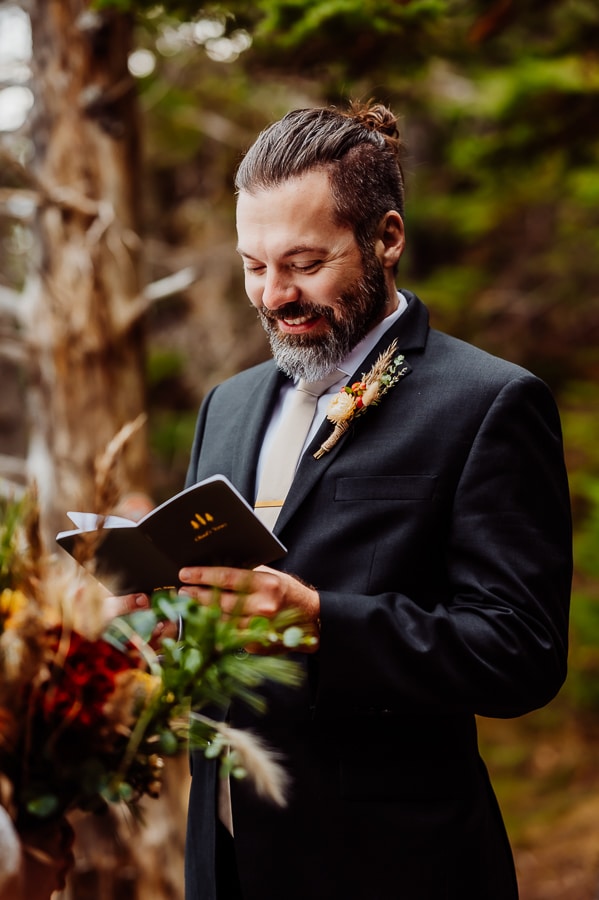 groom smiling and holding vow book during elopement ceremony