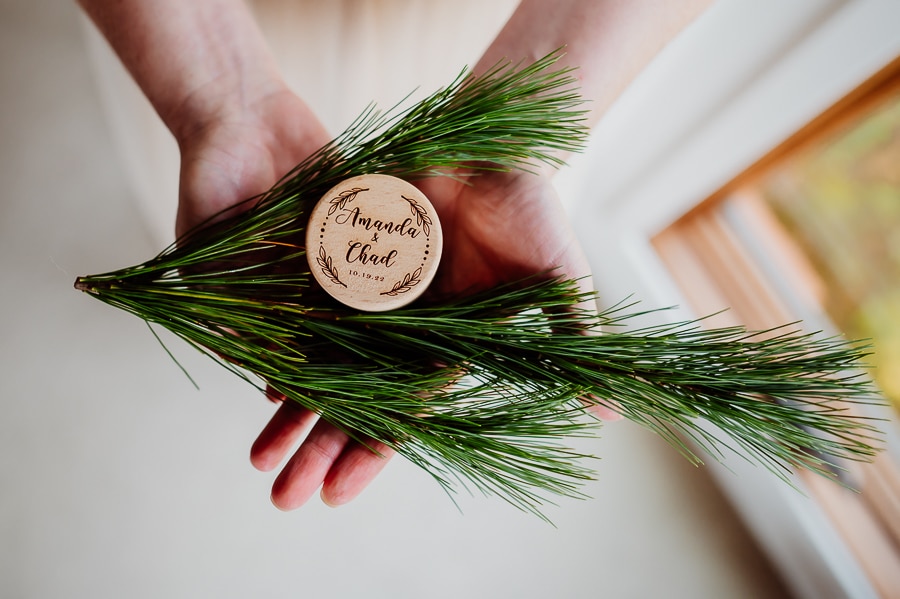 Hands holding pine branch with wedding ring box on top