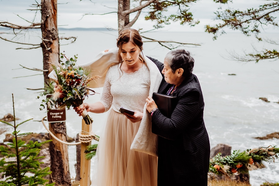 wedding officiant putting shawl over brides shoulders