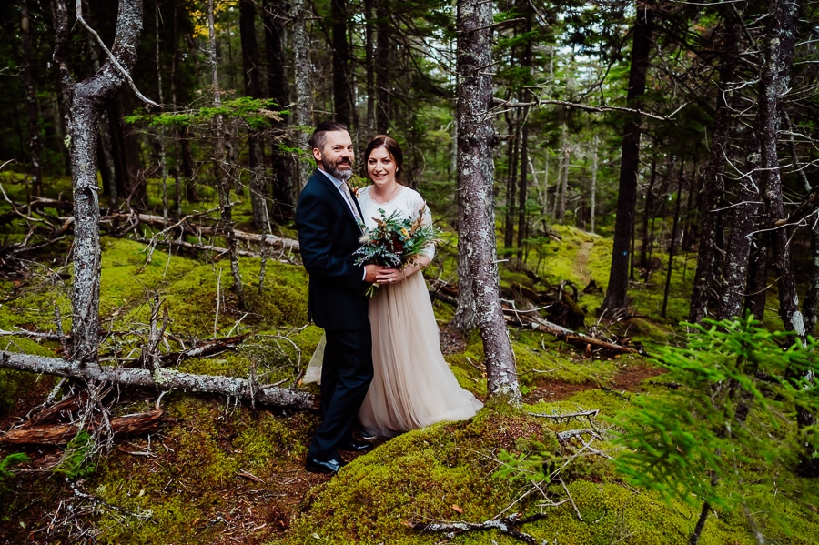 Bride and groom standing in woods with moss everywhere