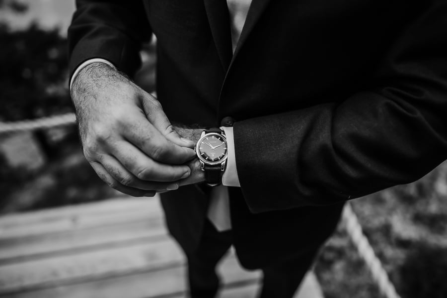 Groom adjusting watch on wrist in black and white