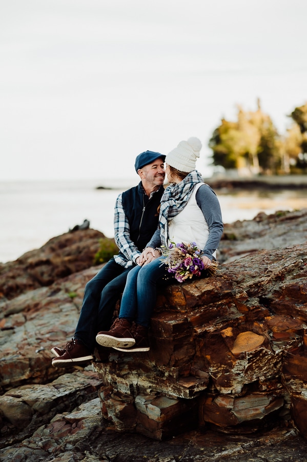 Engaged couple sitting on rock near shore path bar harbor
