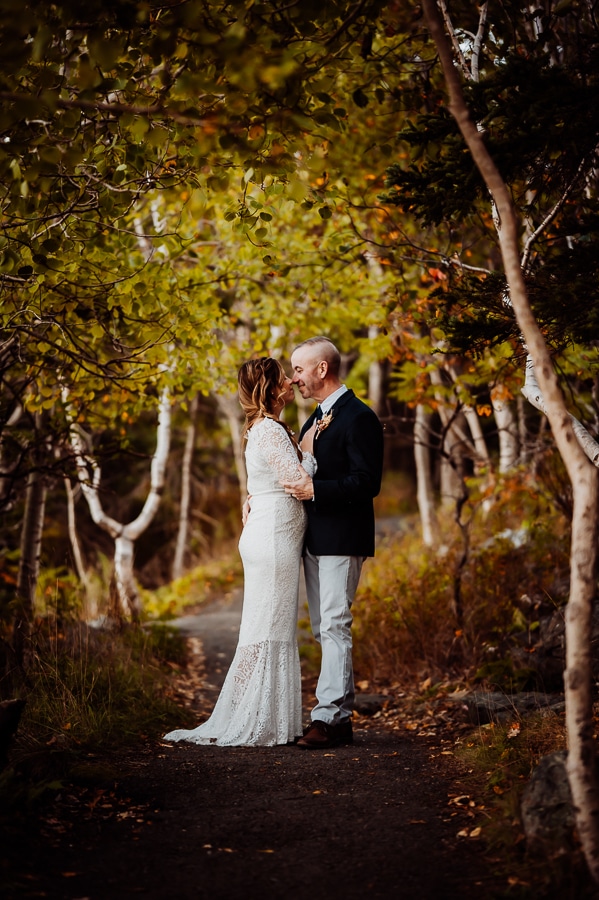 Bride and groom embracing each other in the woods with birch trees
