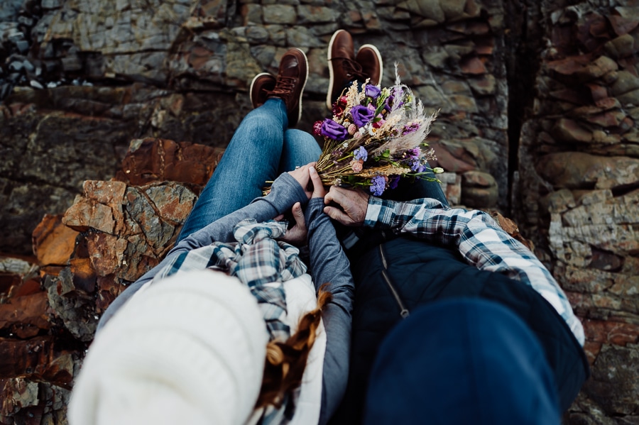 Couple sitting on Rockledge together from above holding bridal flowers