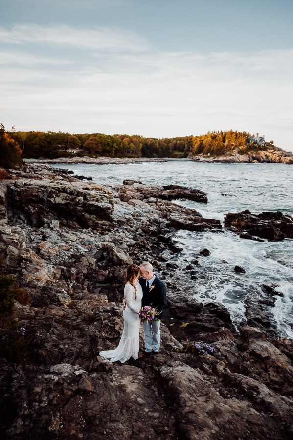 Bride and groom in front of coastal shoreline in Acadia national park