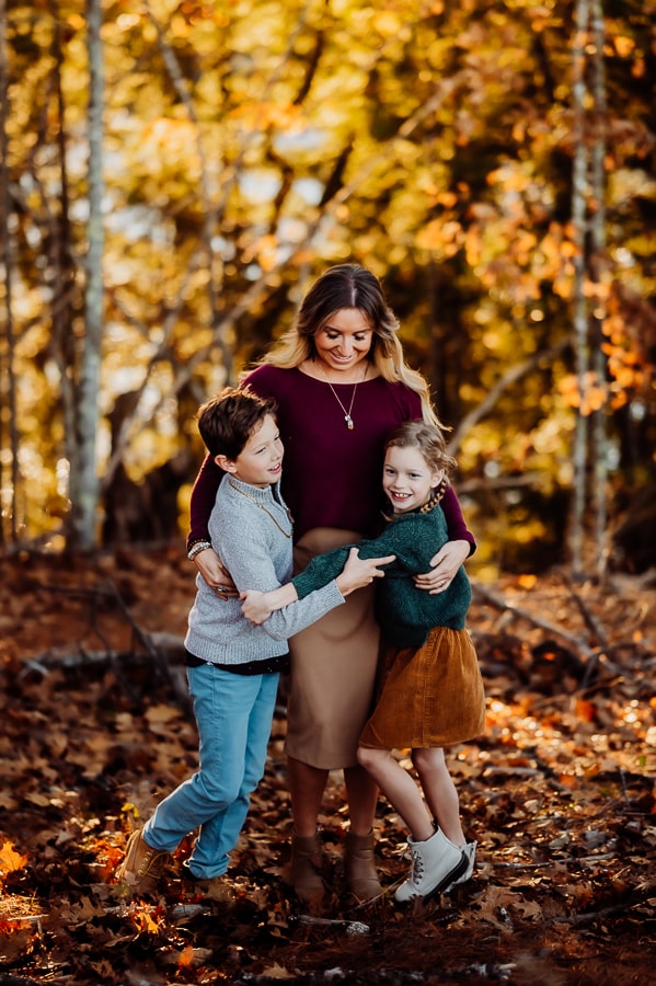 Mother with son and daughters in front of fall leaves in the woods