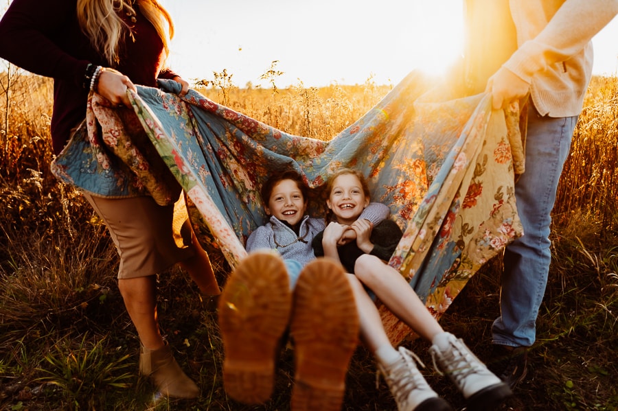 Boy and girl swinging on blanket for family photos
