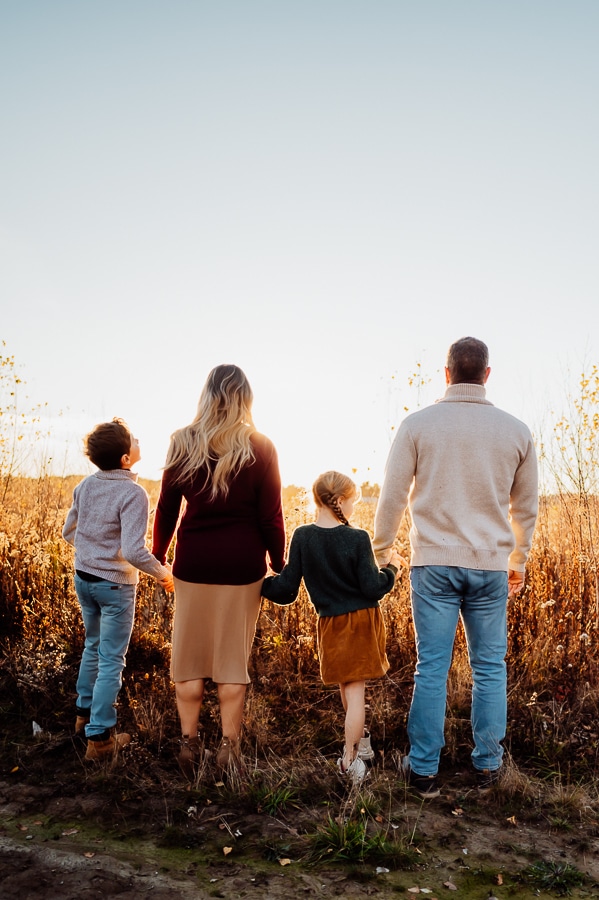 Family of four standing back to camera holding hands