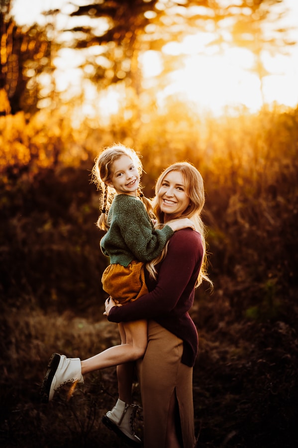 Mother and daughter smiling at golden hour sunset