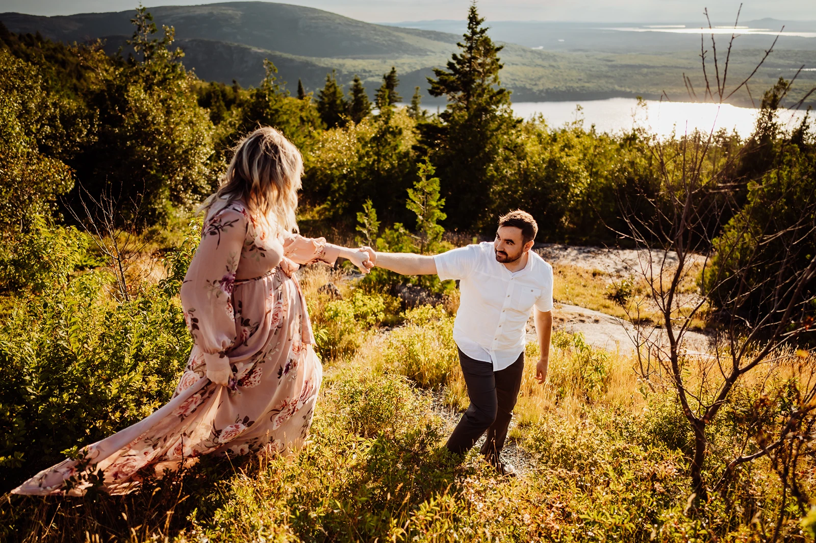 Man leading woman wearing pink floral dress down path on cadillac mountain